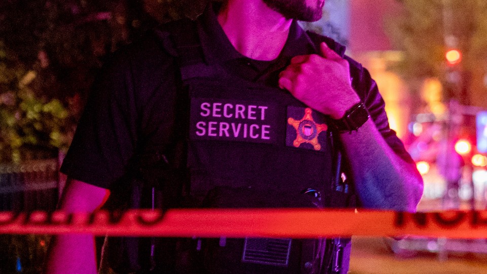 Man in a Secret Service vest at night time