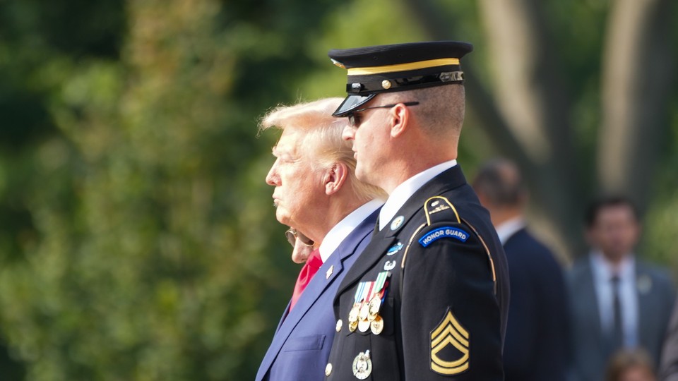 Donlad Trump stands next to an Honor Guard member during a visit to the Arlington National Cemetery