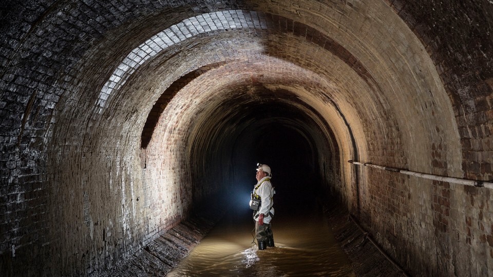 A worker examines brickwork in a London sewer.