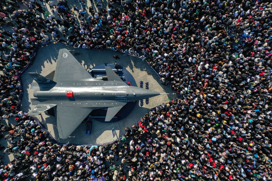 An aerial view of an unmanned combat aircraft surrounded by a crowd