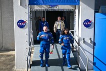 NASA astronauts Barry "Butch" Wilmore and Sunita "Suni" Williams walk out of a NASA building in their blue Boeing spacesuits