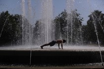 a man doing a pushup in the middle of a large water fountain