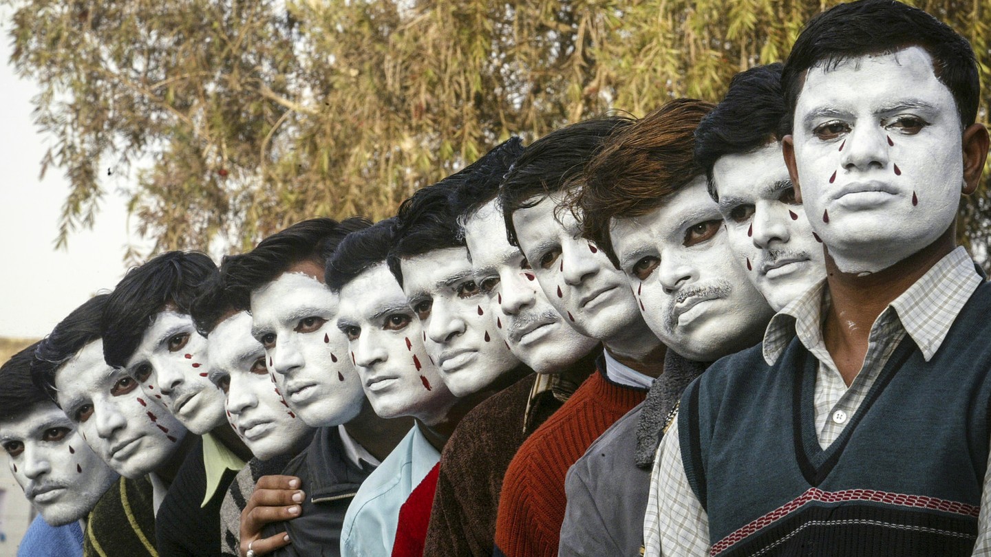 Teachers working on contract pose with their painted faces during a protest in the northern Indian city of Chandigarh. They are standing in a row.