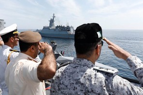 An image of local officials and navy personnel saluting a ship in the Gulf of Oman.