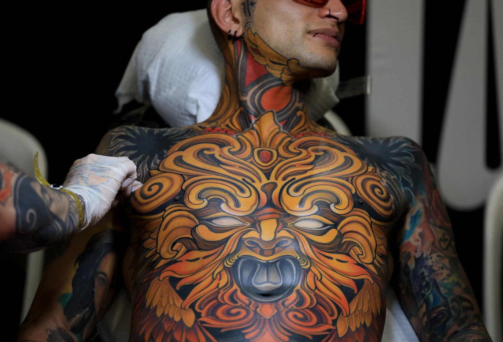 A close view of a person's chest that is completely covered in colorful tattoo art