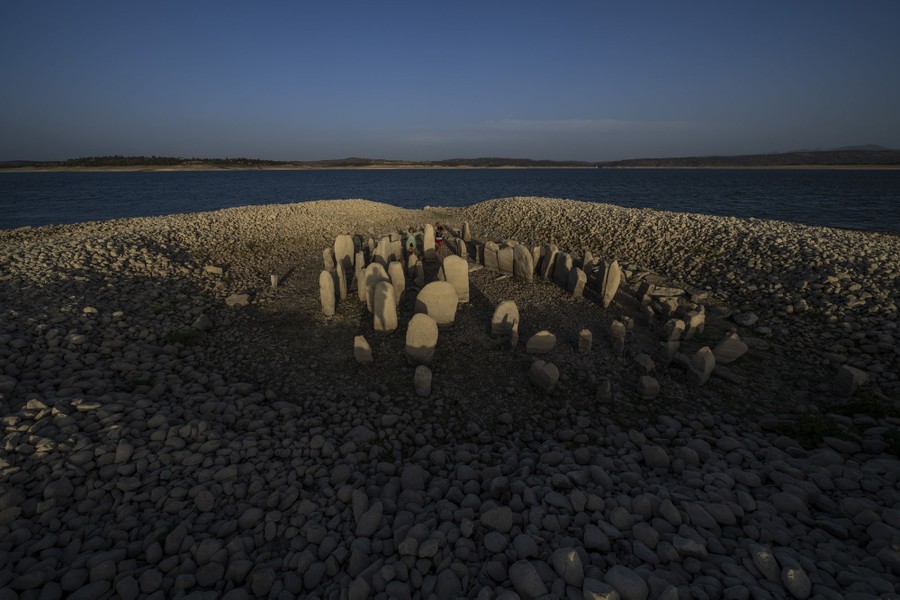 Large stones placed in a rough circle stand amid other small rocks recently surfaced in a reservoir with low water.