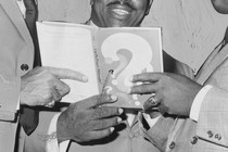 Three pairs of hands hold one book.