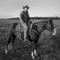 A photograph of Taylor Sheridan on a horse in a field.