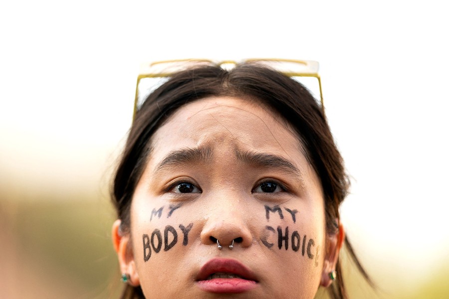 A close view of a protester with the words "my body, my choice" written on her face.