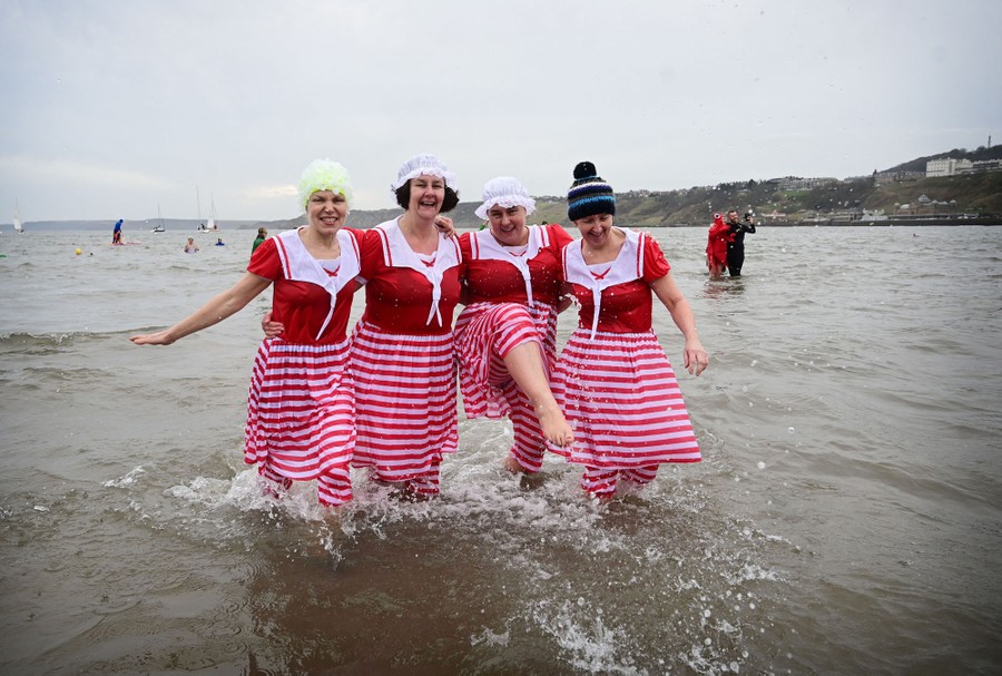 Four people wearing costumes splash in knee-deep water.