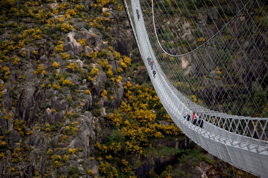 People walk on a very long suspension bridge.