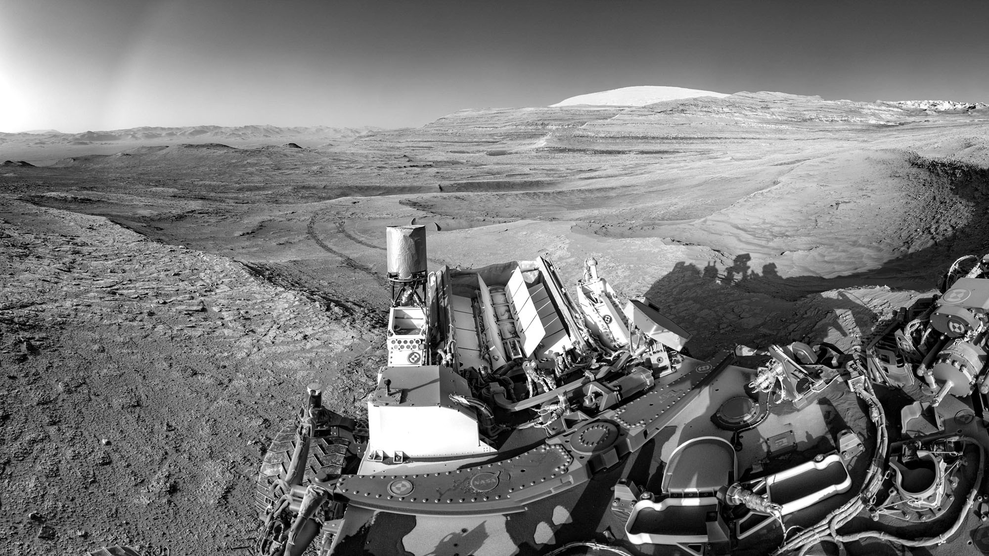 A partial selfie of a Mars rover, looking out over a rocky landscape