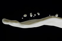 a stream of white liquid splashing onto a dark background from the right side of the image