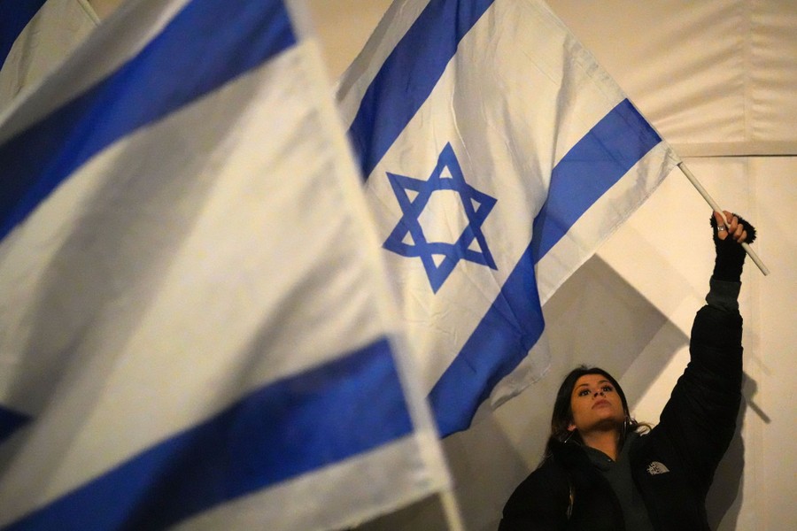 A person waves a large Israeli flag during a protest.