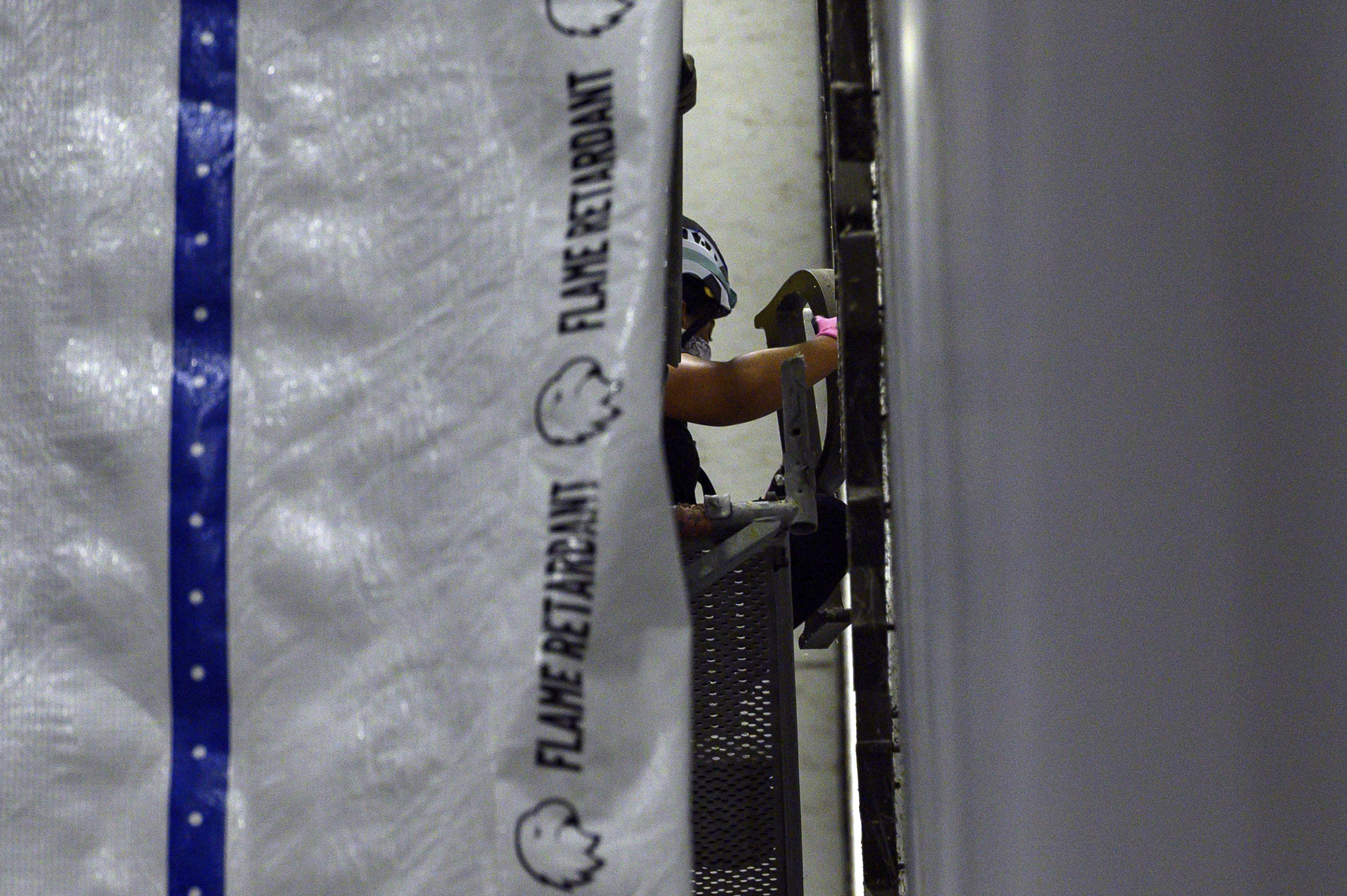 Seen behind a tarp, a worker removes a letter from the wall of