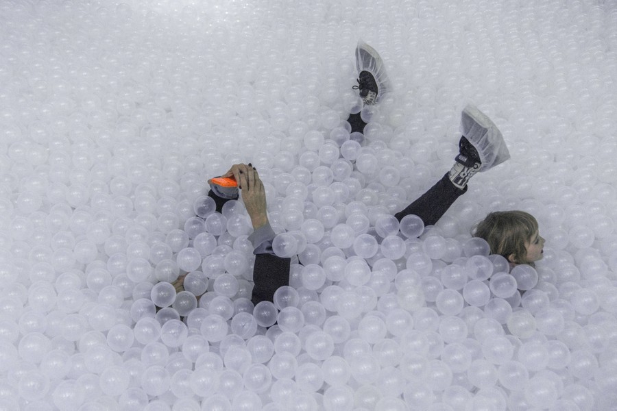 A woman takes a selfie in a pool of plastic balls.