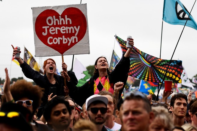Supporters of Jeremy Corbyn hold up a placard at a music festival.