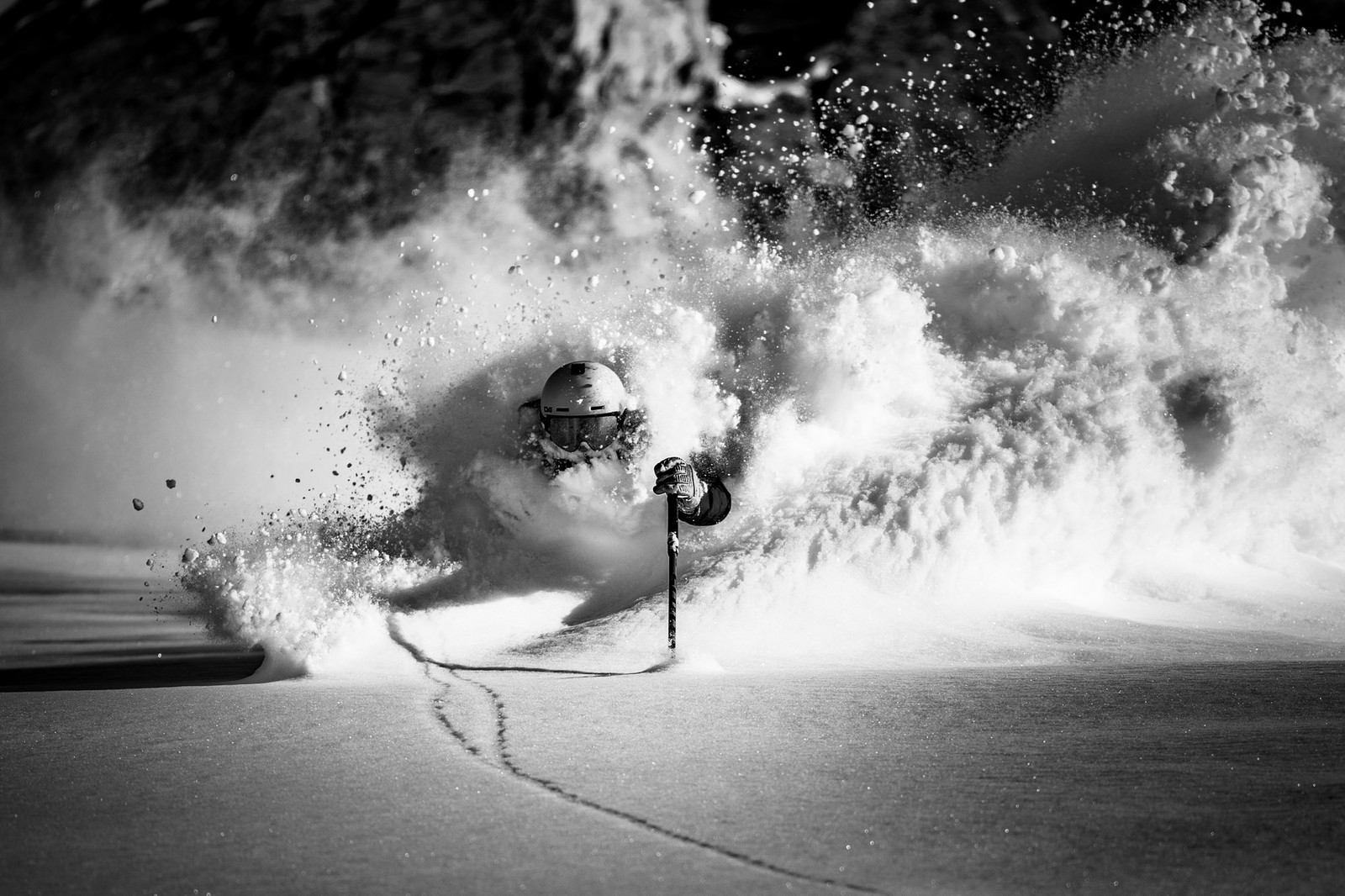 A skier plows through deep powdery snow, sending plumes into the air.