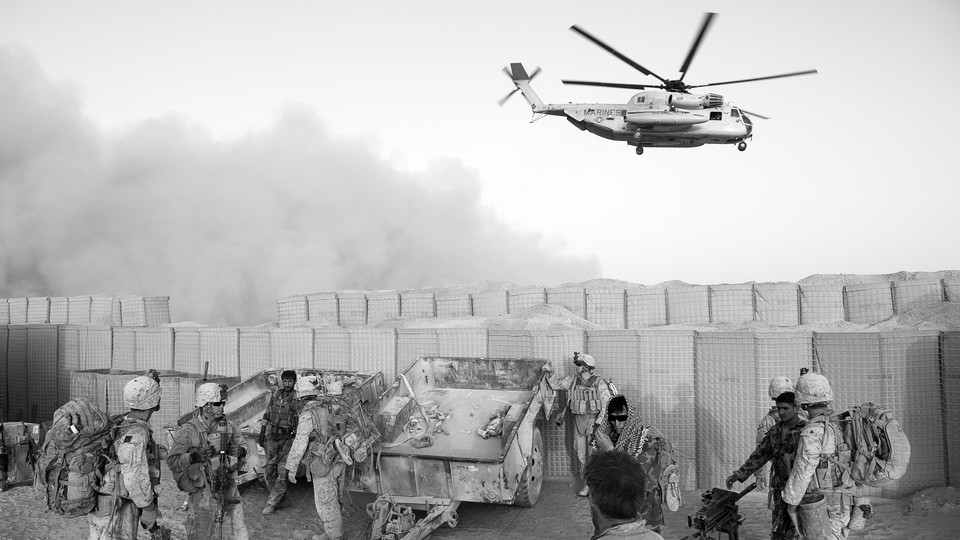 A black-and-white photo of U.S. soldiers in Afghanistan with a helicopter overhead