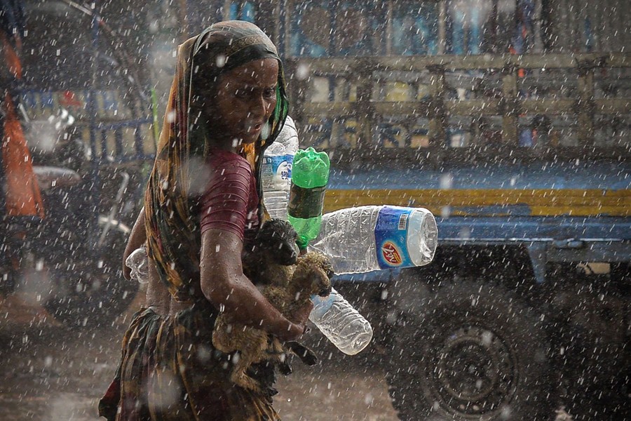 A woman carrying lambs and plastic bottles seeks shelter during a downpour.