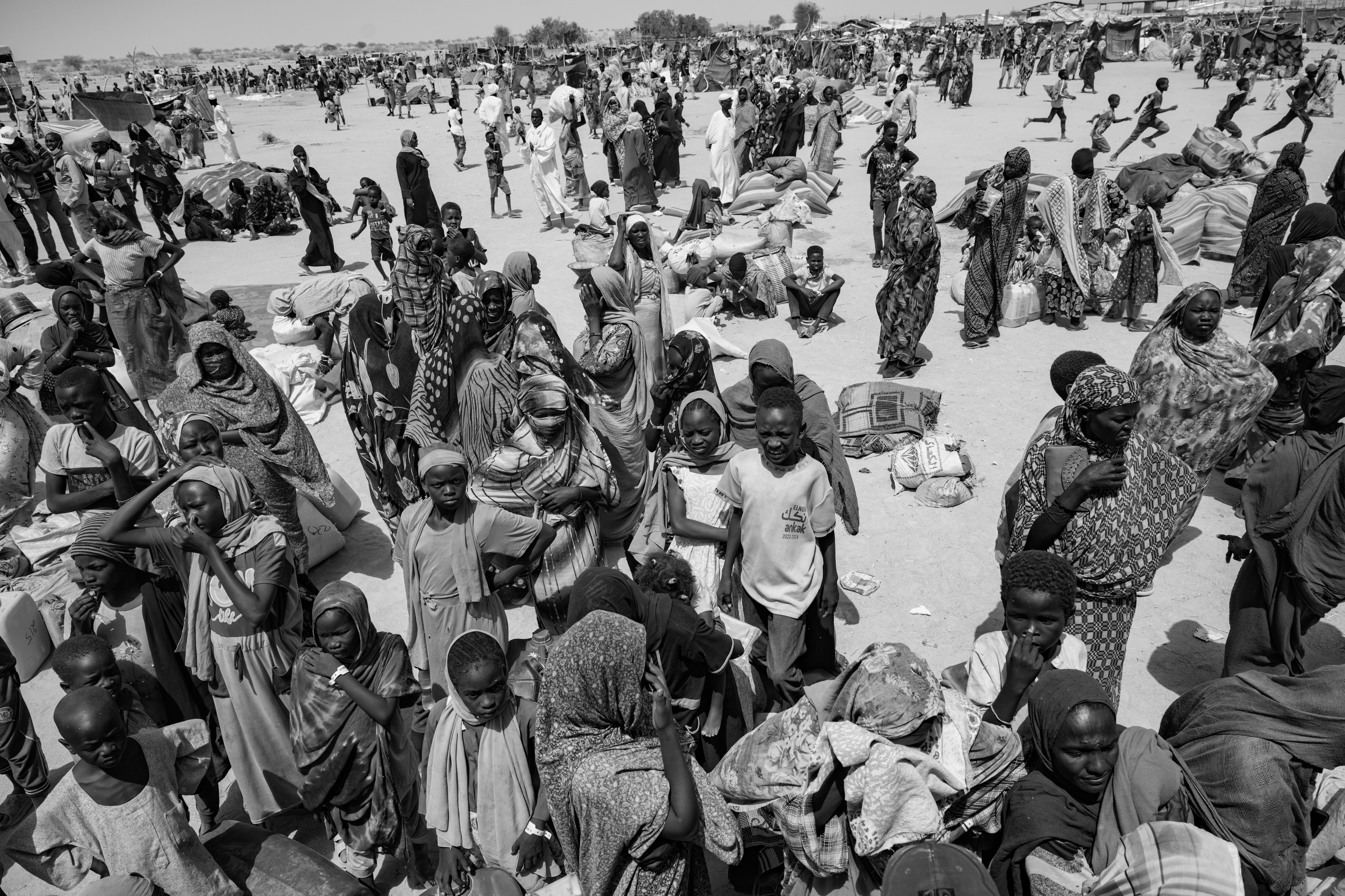Picture of Sudanese refugees gathering in the sweltering sun near a United Nations truck in the Tiné transit camp. 