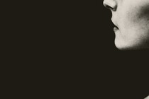 Half of a woman's face in profile against a black background