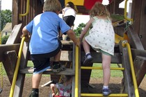 A boy and girl climb up a swing set. 