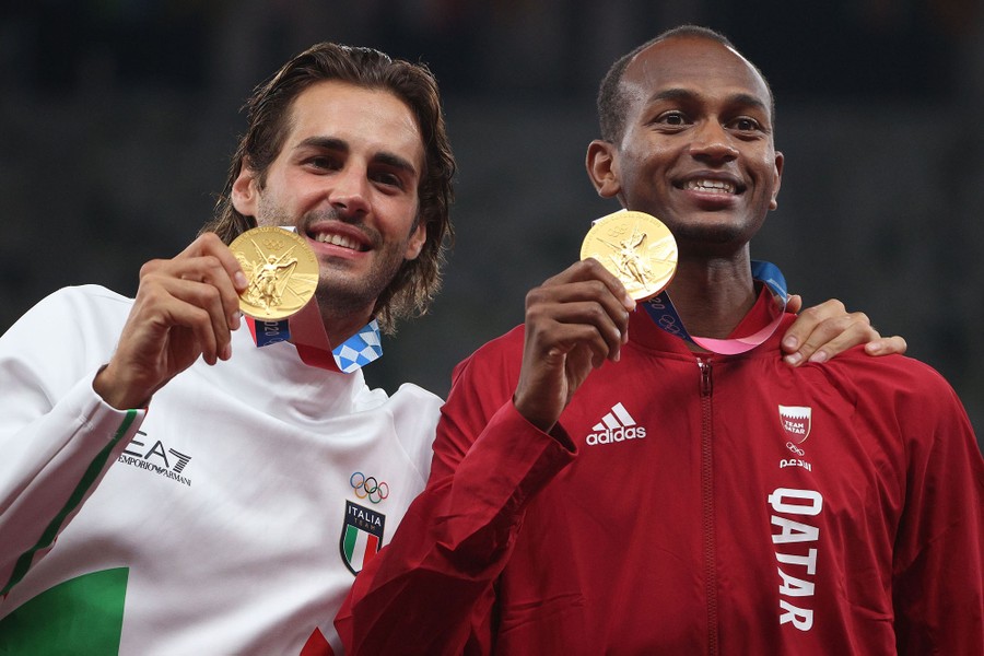 Two athletes hold up their gold medals, shared for winning the high jump.
