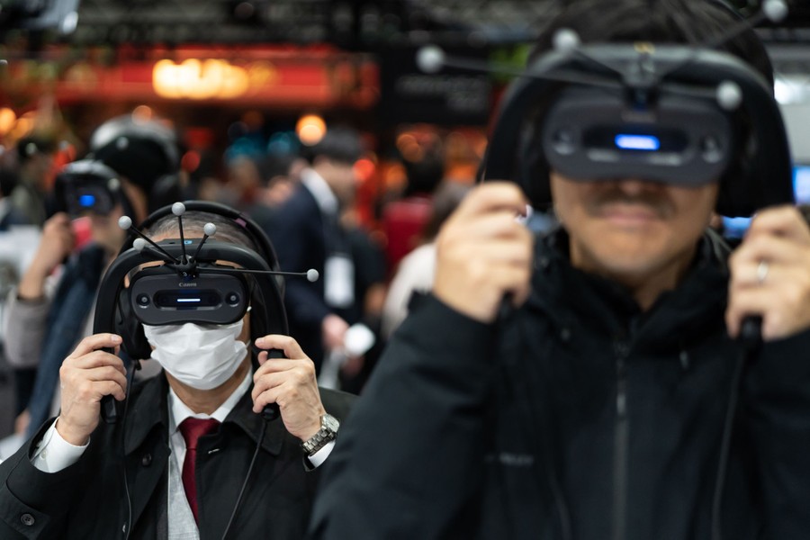 Several people try on VR headsets at a trade show.