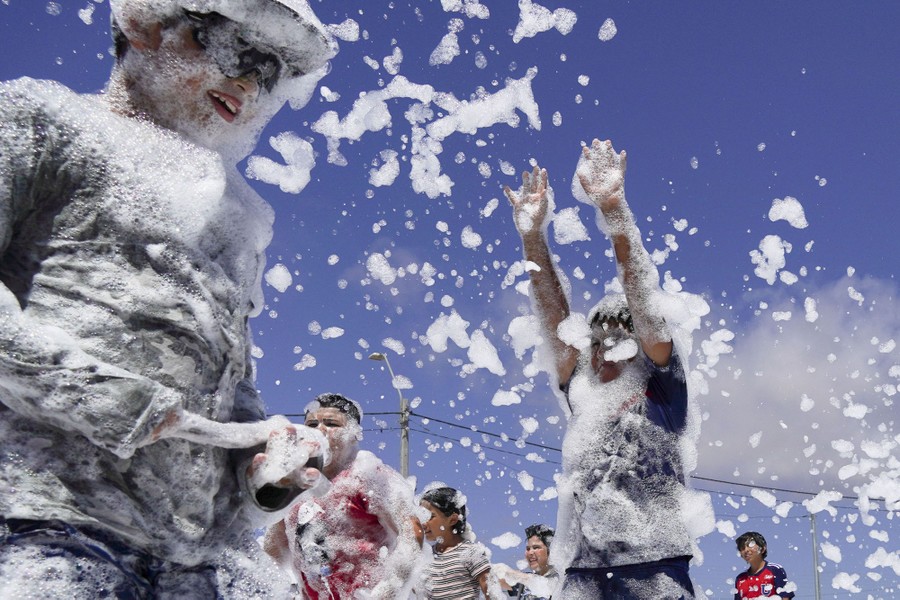 Children covered in soap foam play outside.