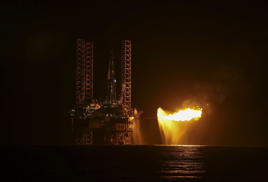 A flare burns from an offshore natural-gas platform at night.