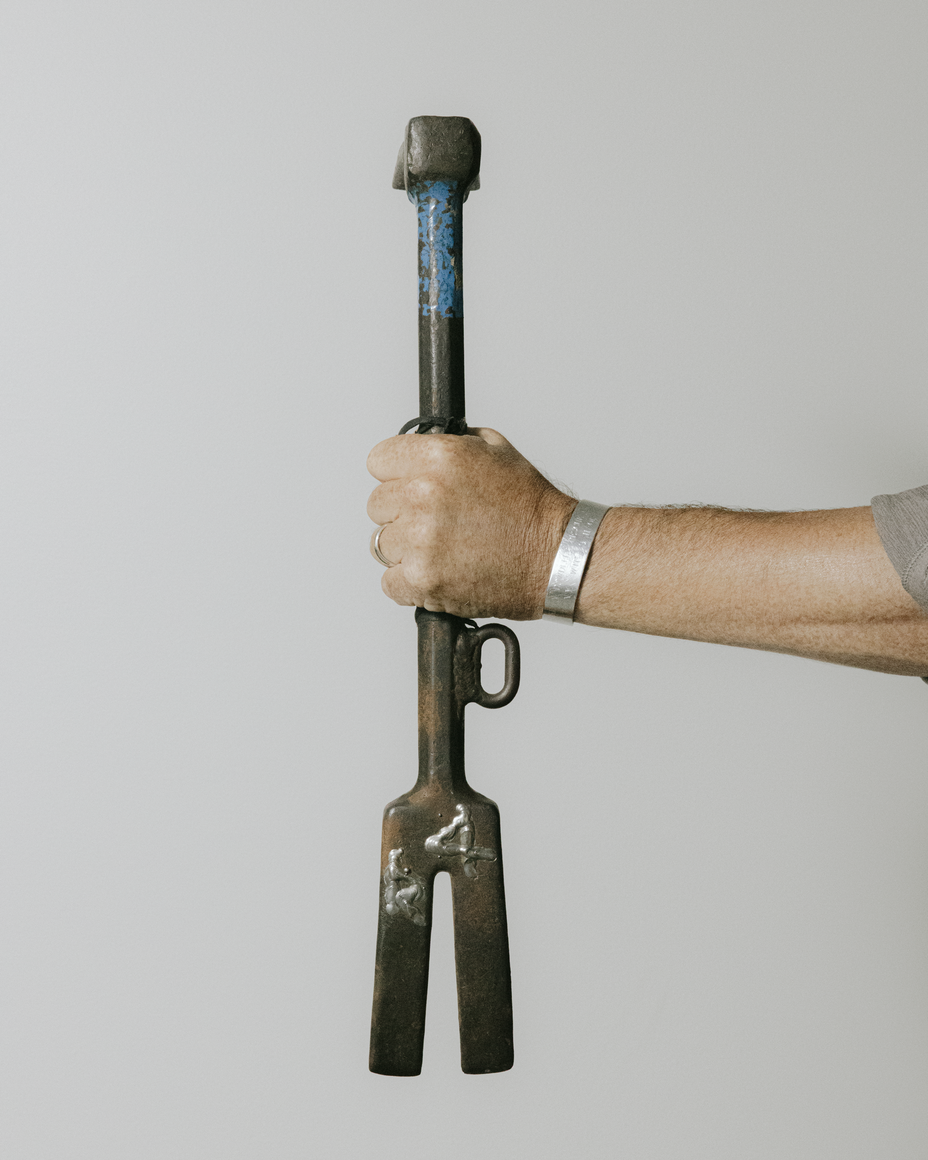 photo of man's arm holding a large metal firefighting tool