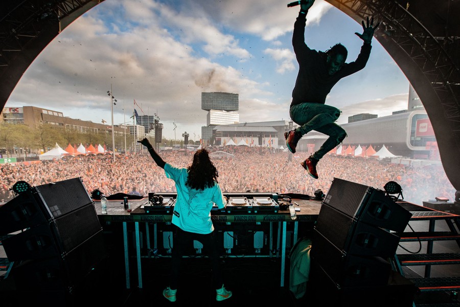 A pair of DJs perform in front of a big festival crowd.
