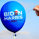 Hand with a needle about to puncture a "Biden Harris 2024" bubble