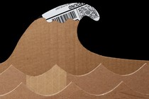 Photo of 2 rows of waves cut out of cardboard boxes, with large cardboard tsunami wave that has a white crest made of white/black shipping label