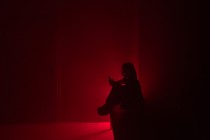 Photograph of a child looking at a phone in a dark room with a dim red light