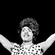 Black and white photo of Little Richard in a patterned vest and flashing peace signs