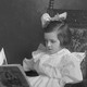 A photograph of a child reading a children's book while sitting in a large chair
