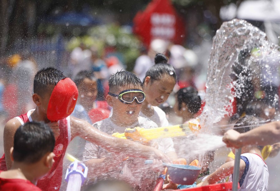 Children play, squirting and splashing water at one another.