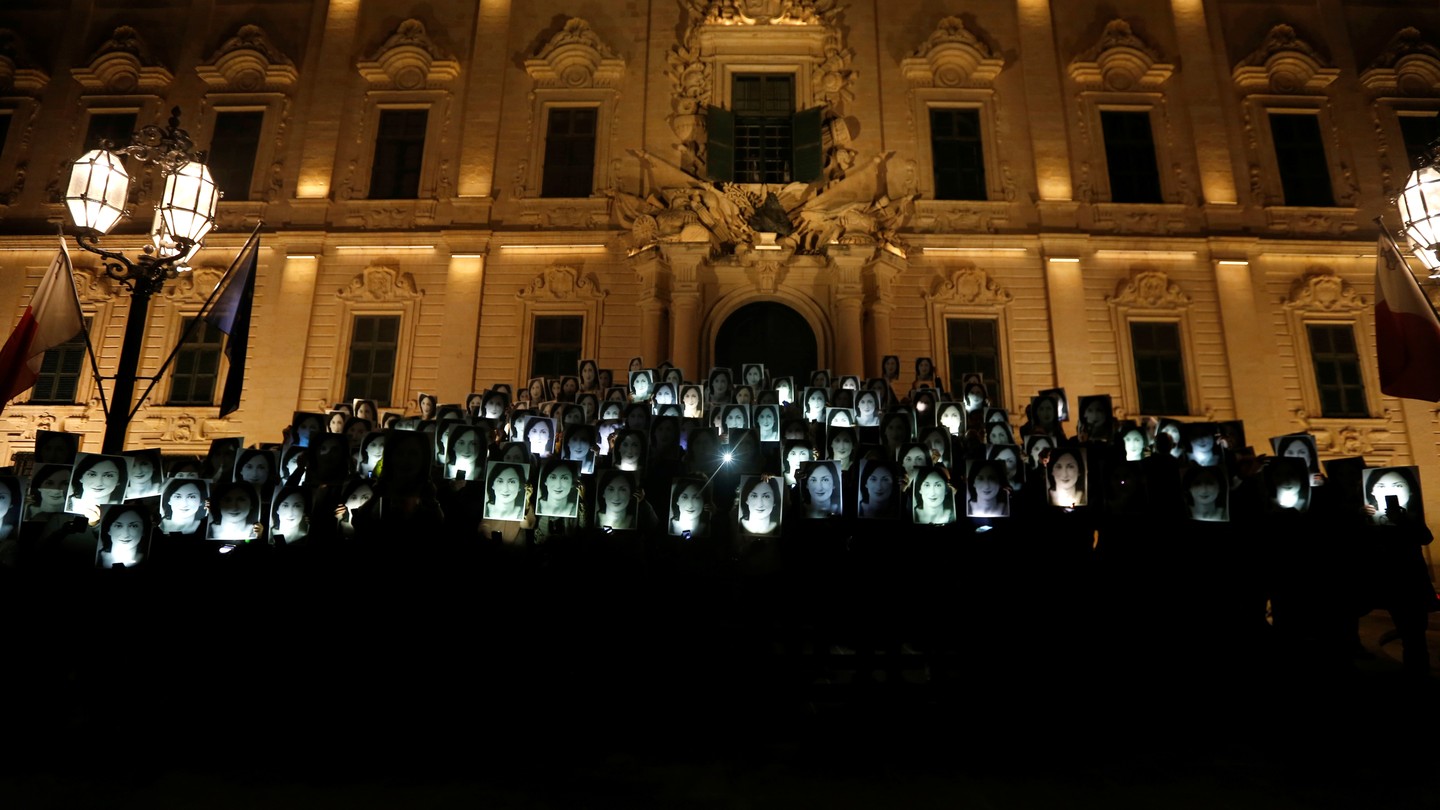 People standing outside a building hold up photos of Daphne Caruana Galizia during a protest.