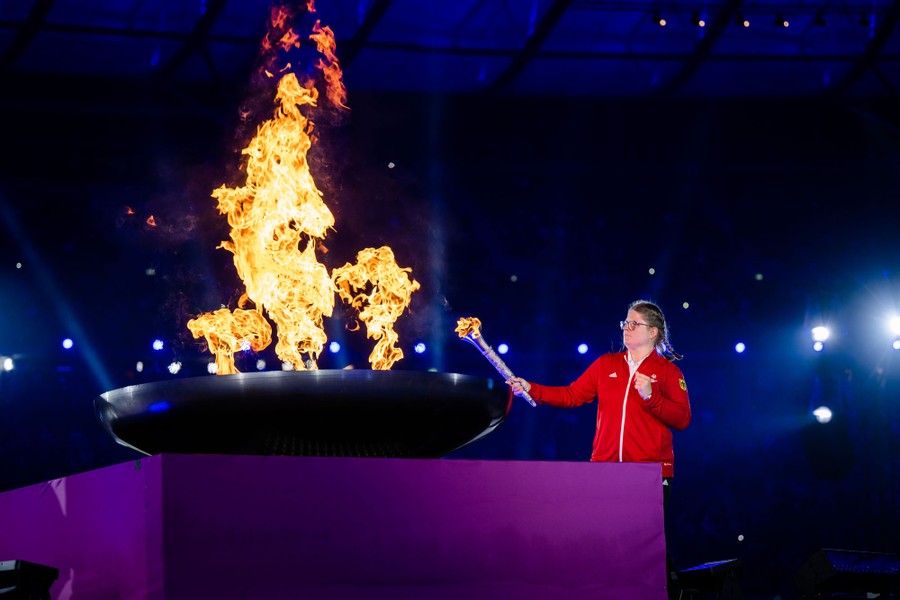 An athlete uses a torch to light a large ceremonial cauldron.