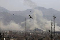 Birds fly over Tehran, with clouds of smoke visible in the background