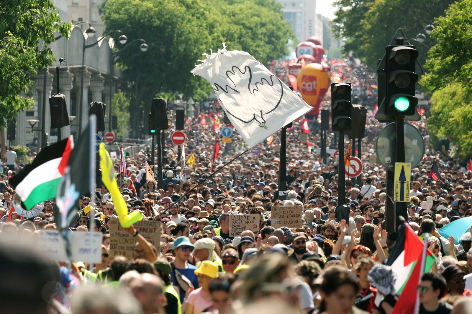 A large crowd of demonstrators marches in a city street.