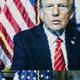 Todd Blanche and Donald Trump sit next to each other in front of American flags.