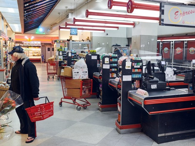 a man in a grocery store near the checkout lines in the early morning while the rest of the store is mostly empty