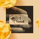 A hand holds an "I Voted" sticker.