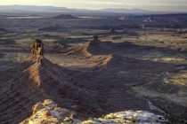 Cedar Mesa Valley of the Gods in Utah. Rock formations rise out of red soil.