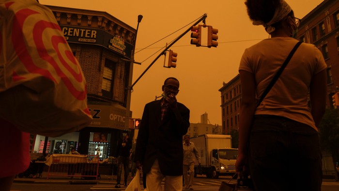 A group of people walking under an orange sky