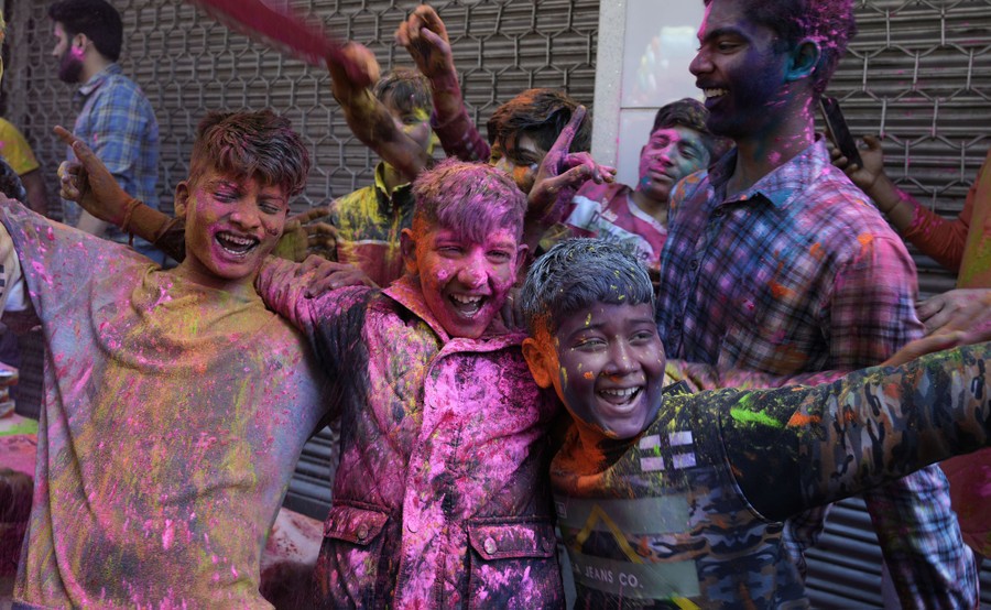A group of boys covered in colored powder laugh together.