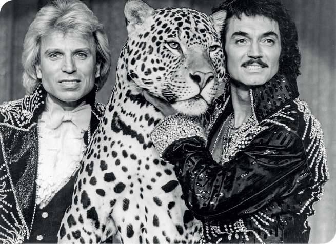A photograph of Sigfried and Roy with a leopard.